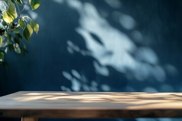 Poster - Empty wooden table with sunlight and leaf shadows on a dark blue background.