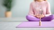© MAY - A yoga mat laid out on a wooden floor with a purple meditation cushion and a burning incense stick, inviting relaxation and mindfulness.