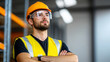 © KayKai - A man wearing a yellow vest and a hard hat stands in a warehouse