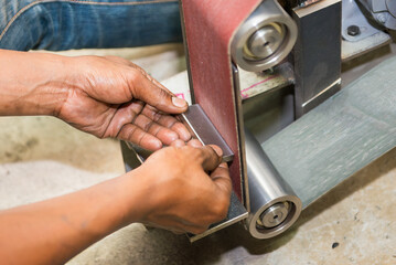 Wall Mural - The metal deburring process by abrasive sand paper belt.