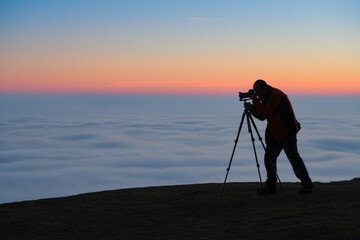 silhouette of a photographer on a hill with an inversion at sunset. nature and mountain photography