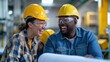 © Vilaysack - Two cheerful workers in safety gear laugh together in a factory setting, showcasing teamwork and a positive work environment.