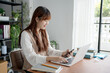 © Charlie's - Asian woman using laptop to study student engaged in online learning at college.