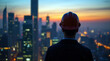 © Evgen - A silhouette of a worker in a hard hat looking over a vast city, signifying the impact of labor on urban development