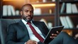 © JoxyAimages - A composed and stylish man is seated while analyzing information on his tablet, showcasing modern technology at play in a professional and sophisticated office environment.