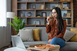 © Liubomir - Asian woman enjoys pizza while watching laptop at home. Relaxed and casual atmosphere highlights leisure, technology, and comfort. Perfect depiction of modern lifestyle.