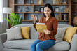 © Liubomir - Asian woman sitting on cozy couch reading letter with happy expression. Comfortable home setting conveys joy and surprise as she receives message. Warm and inviting interior.