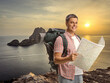 © Ljupco Smokovski - Young man with a backpack holding a tourist map on a cliff across Es Vedra on Ibiza island