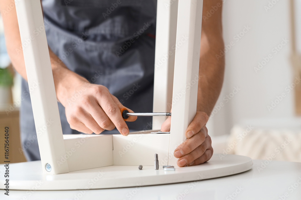 Male carpenter tightening screw in table with screwdriver, closeup