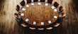 © Huzaifa - A high-angle view of a large round table in a boardroom with business executives in a strategic meeting, set in a modern office.