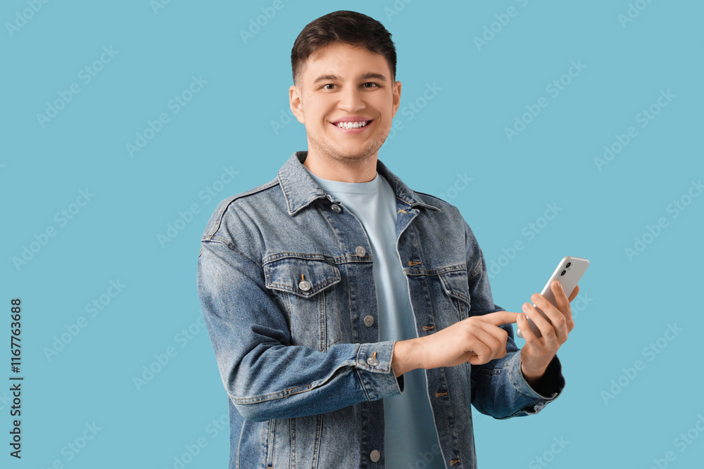 Handsome young happy smiling man with mobile phone on blue background