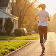 © Olesia - Young woman jogging in the early morning sunlight along a residential street