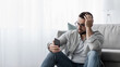 © Prostock-studio - Relationship problems, facial expressions, bad news and messages, negative, stress and sad. Unhappy young handsome man in glasses sits on floor in living room interior reads message on smartphone