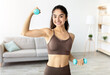 © Prostock-studio - Portrait of smiling Indian woman doing domestic training, exercising with dumbbells, strengthening biceps at home. Fit Eastern lady making whole body strength workout, leading active lifestyle