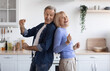 © Prostock-studio - Joyful elderly spouses dancing together at kitchen, happy attractive senior man and woman in casual standing back to back and making dance moves, enjoying weekend at home, copy space