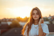 © NaphakStudio - young woman with long hair poses thoughtfully at sunset, wearing casual attire and jewelry.