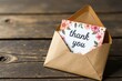 © Udomner - Thank you card inside a modern brown envelope on a rustic wooden table, gratitude, expression
