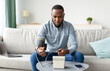 © Prostock-studio - African American Young Man Measuring Arterial Blood Pressure Having Hypertension Problem Sitting On Sofa At Home. High Blood-Pressure And Hypotension Issue