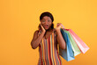 © Prostock-studio - Excited black female with shopping bags touching her face in surprise, cannot believe huge sale on orange studio background. Pretty African American woman buying on discount