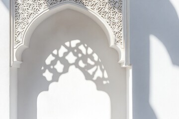 Poster - Intricate white archway with ornate design casting shadow on wall.