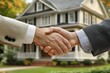 © saleha - Two business professionals shake hands in front of a charming house during a property transaction on a sunny day