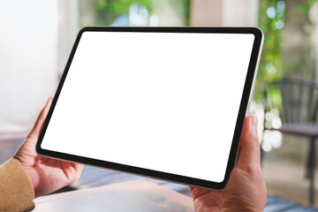 Wall Mural - mockup image of a woman holding digital tablet with blank desktop screen in cafe