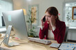© crizzystudio - Young asian businesswoman looking at computer screen and having a stressful phone call in the office, she's having a headache and feeling tired from overworking