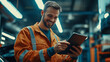 © Karina Korytchenko - A mechanic in an orange uniform using a tablet for digital repair information in a modern workshop during the day. Generative AI