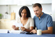 © Antonioguillem - Interracial couple calculating expenses in the kitchen