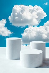 Wall Mural - three white cylindrical podiums against a blue sky with fluffy clouds.