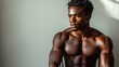 © Kalivmasa - A shirtless muscular Black man sits in a chair with his arms crossed, looking to his right with a serious expression.