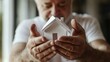 © Chanwit - Elderly man holding miniature house home environment lifestyle content warm indoor setting focus on care and community