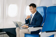 © Nuttapong punna - Young Asian executive excels in first class, multitasking with digital tablet, laptop and smartphone.