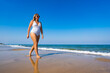 © Jacek Chabraszewski - Summertime by sea. Beautiful middle-aged woman walking on sandy beach on sunny summer day. Front view