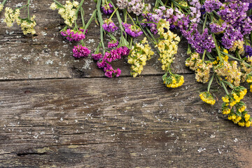 Wall Mural - Multicolored limonium flowers on a rough wooden background. flat lay top view. copy space. rustic floral natural background. seasonal horizontal backgrounds