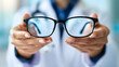 © olenap - Doctors hands holds glasses. Stylish eyewear with reflection in lenses of glasses. symbolizing vision correction and modern style. Optical store or vision correction concept.