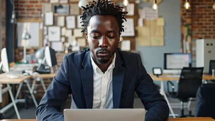 Poster - A serious individual sits at a desk in a contemporary workspace. Surrounded by creative materials, they concentrate on their laptop. The atmosphere reflects innovation and productivity.