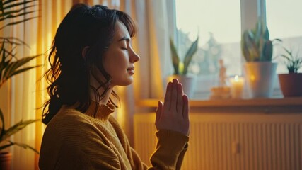 Aufkleber - Warm sunlight filters through a window as a woman engages in meditation at home, creating a serene atmosphere enhanced by potted plants and soft light.