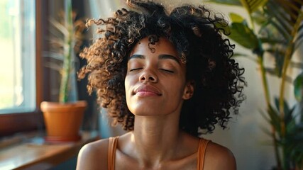 Aufkleber - A woman with curly hair relaxes in a bright, plant-filled room, eyes closed and face peaceful. Sunlight filters through the window, creating a calm atmosphere for mindfulness and relaxation.