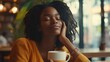 © Johannes - Carefree african american woman sitting in cafeteria drinking coffee while looking away. Black young woman drinking tea while thinking. Smiling girl relaxing and thinking while drinking cappuccino.