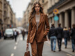 © Sachin - Elegant woman in a mocha brown pantsuit strolls down a city street, exuding confidence and style.