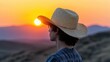 © kvladimirv - Silhouette of a Young Man in Straw Hat Watching Sunset Over Rolling Hills
