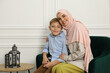 © New Africa - Muslim woman and her son spending time together at home