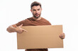 © Volodymyr - Man showing promo holding pointing finger on blank board on studio background. Blank signboard with copyspace. Advertisement concept. Ad board with copy space, blank mockup. Blank signboard, placard.