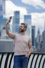 Wall Mural - Man talking at the phone in New York City. Hispanic Man talking on the phone. Guy in t-shirt talking on cell phone. Guy talking by mobile phone. Tourist in city street holding smartphone.