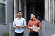 © Liubomir - Two men walking and chatting outside an office building, colleagues and business partners taking a walk in the fresh air on their lunch break.