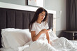 © boryanam - Young Woman sitting in her bed using her phone in the morning