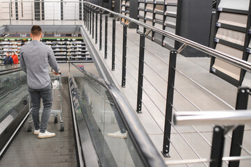 Wall Mural - A man with a shopping cart on an escalator in a hardware store.