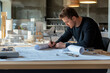 © whitestorm - Architect reviewing blueprints in modern office