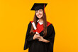 © New Africa - Happy student with diploma after graduation on orange background